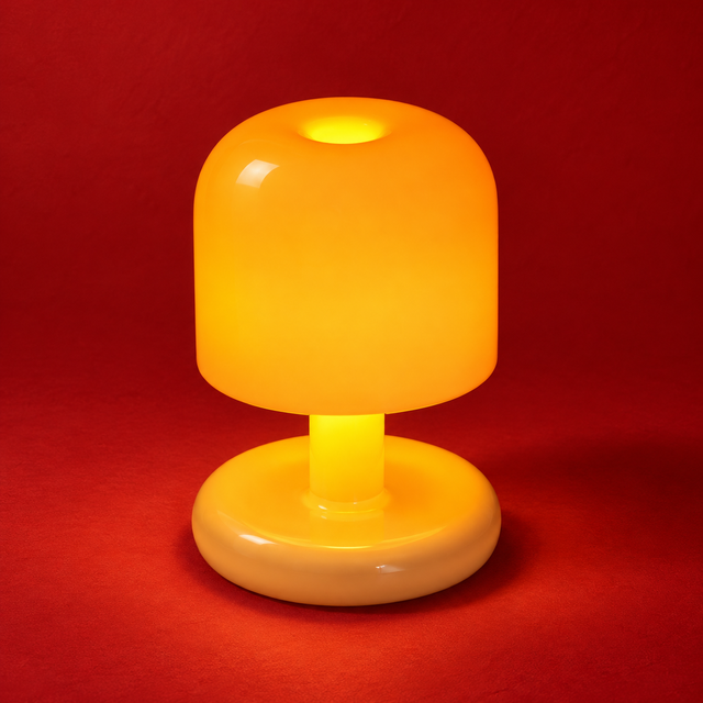 SAHAR sunny yellow dome table lamp glowing warmly against a red studio backdrop
