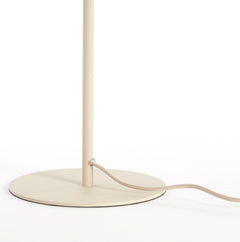 close up on bottom half of thin cream coloured lamp shade with circular base and cream wire leading out