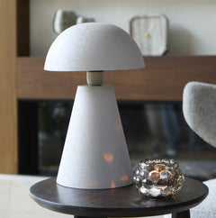 image of smaller light grey matt dome table lamp of a dark oak side table next to a sofa, with small candle votive reflecting light onto its base