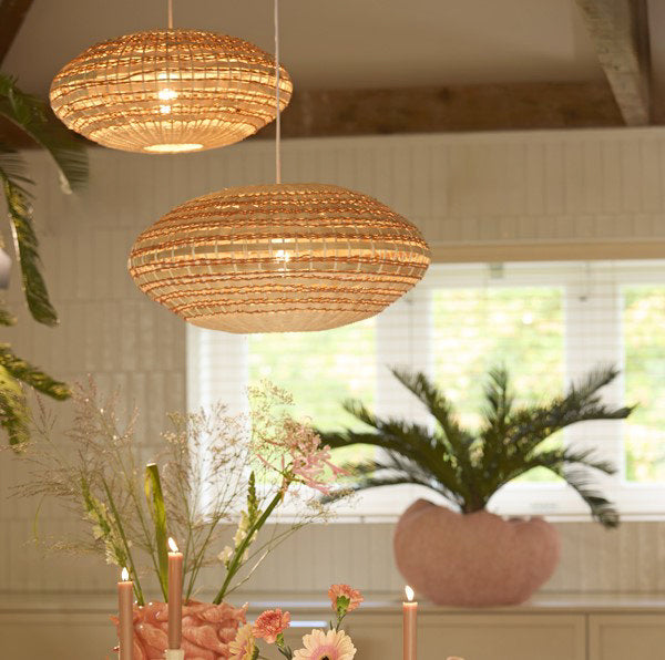 image of two woven oval hanging light shades in a dining room, in natural and terracotta colours