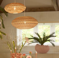 image of two woven oval hanging light shades in a dining room, in natural and terracotta colours