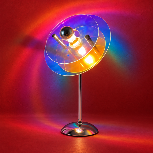Saba iridescent acrylic table lamp with chrome stand, casting rainbow light across a red studio background