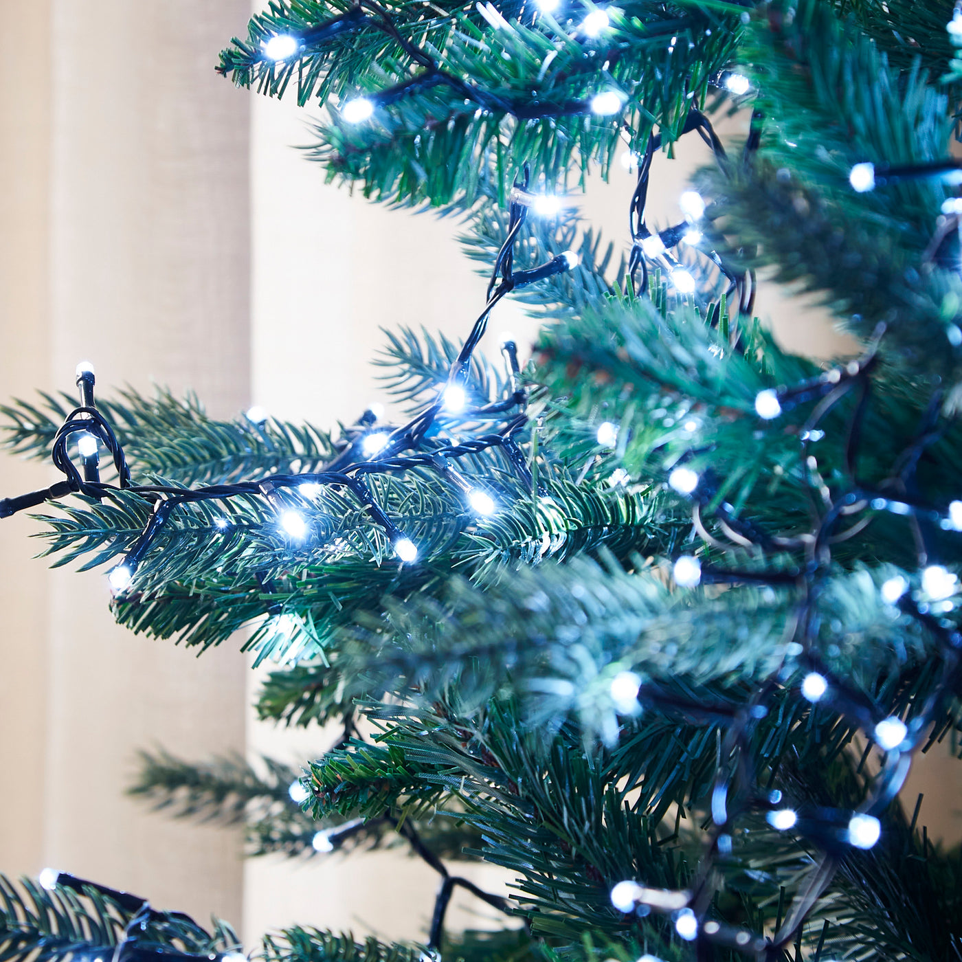 close up on branches of a christmas tree with ice white string lights on