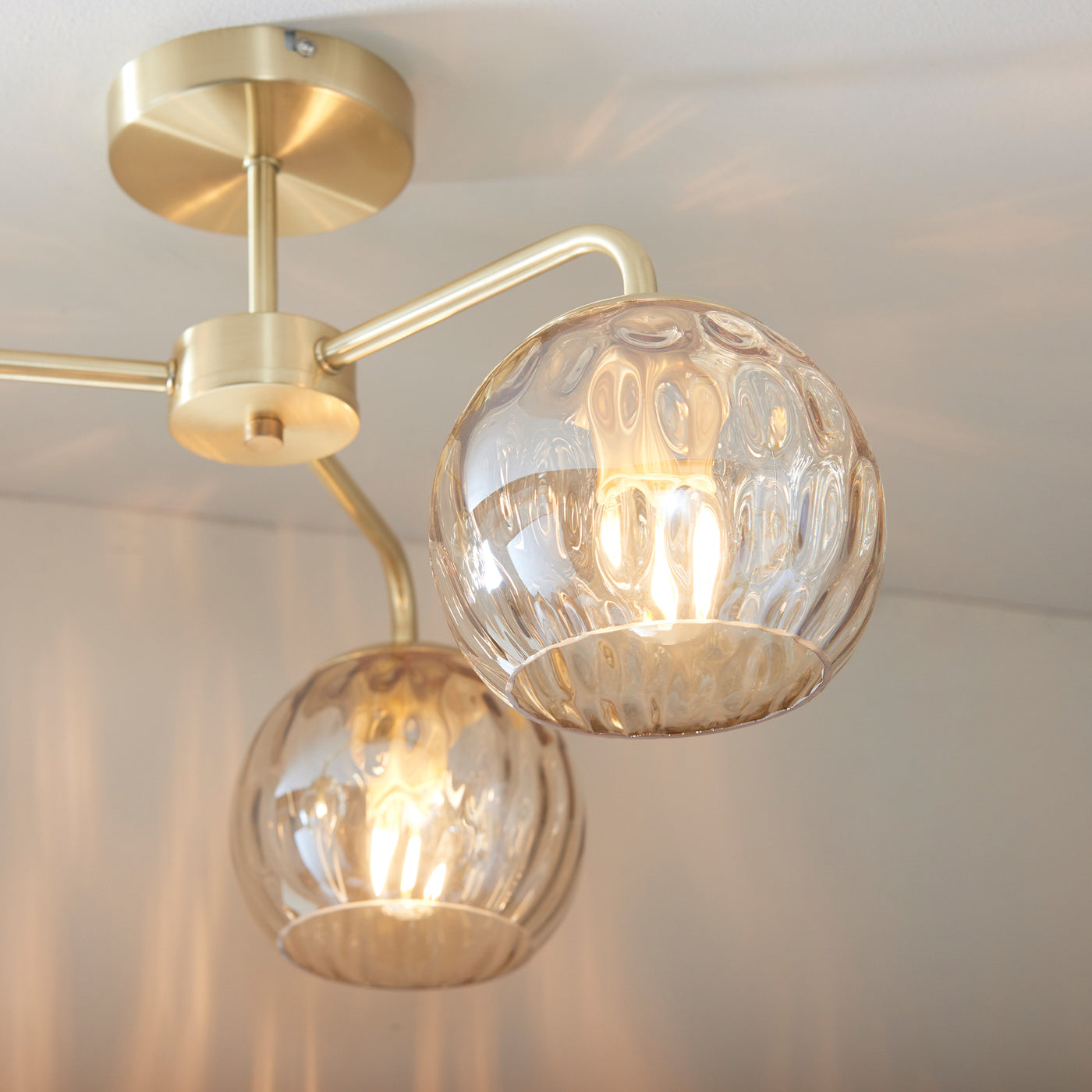 close up on domed dimpled glass shades of champagne ceiling light with satin gold fixture