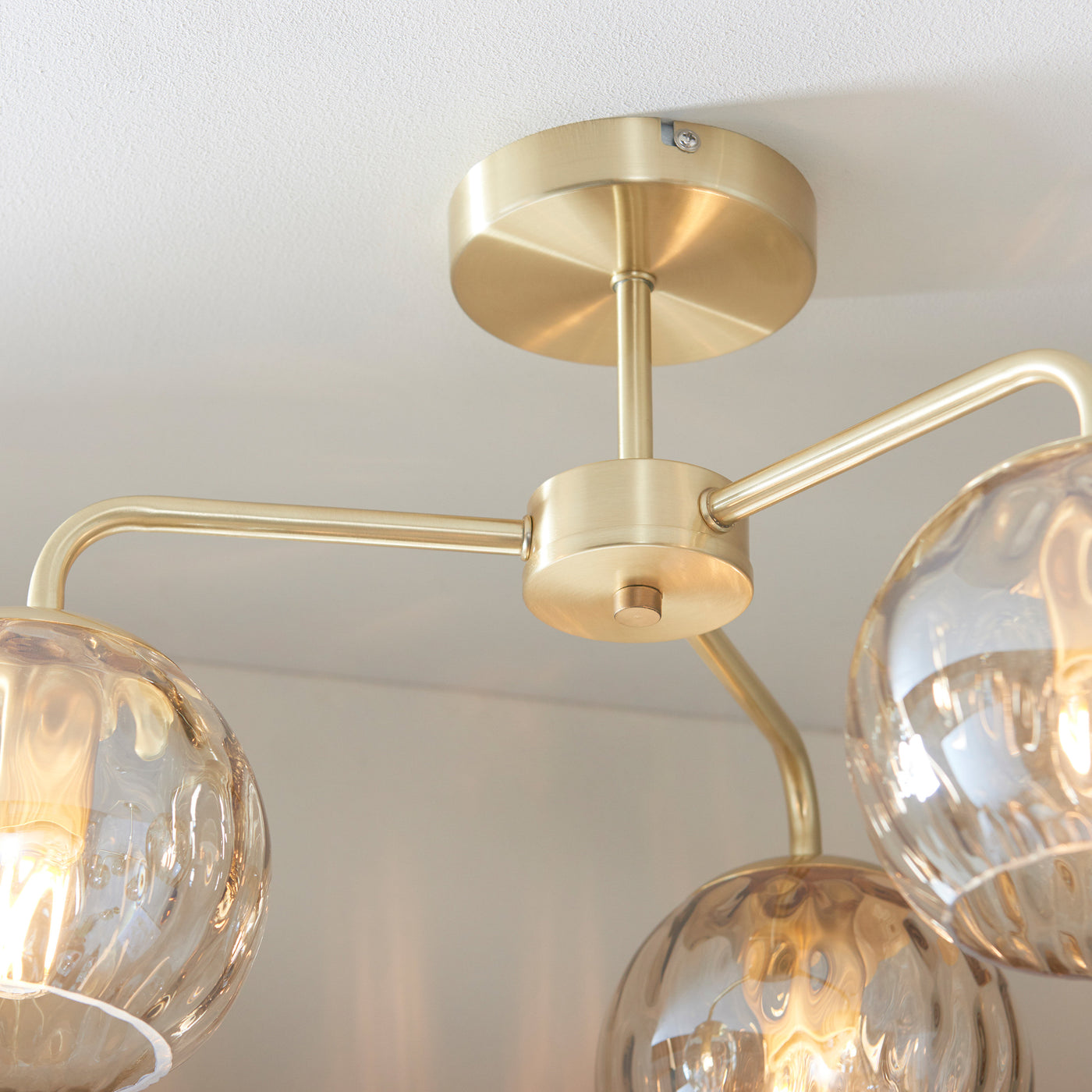 close up on satin gold fixture of dimpled glass ceiling light