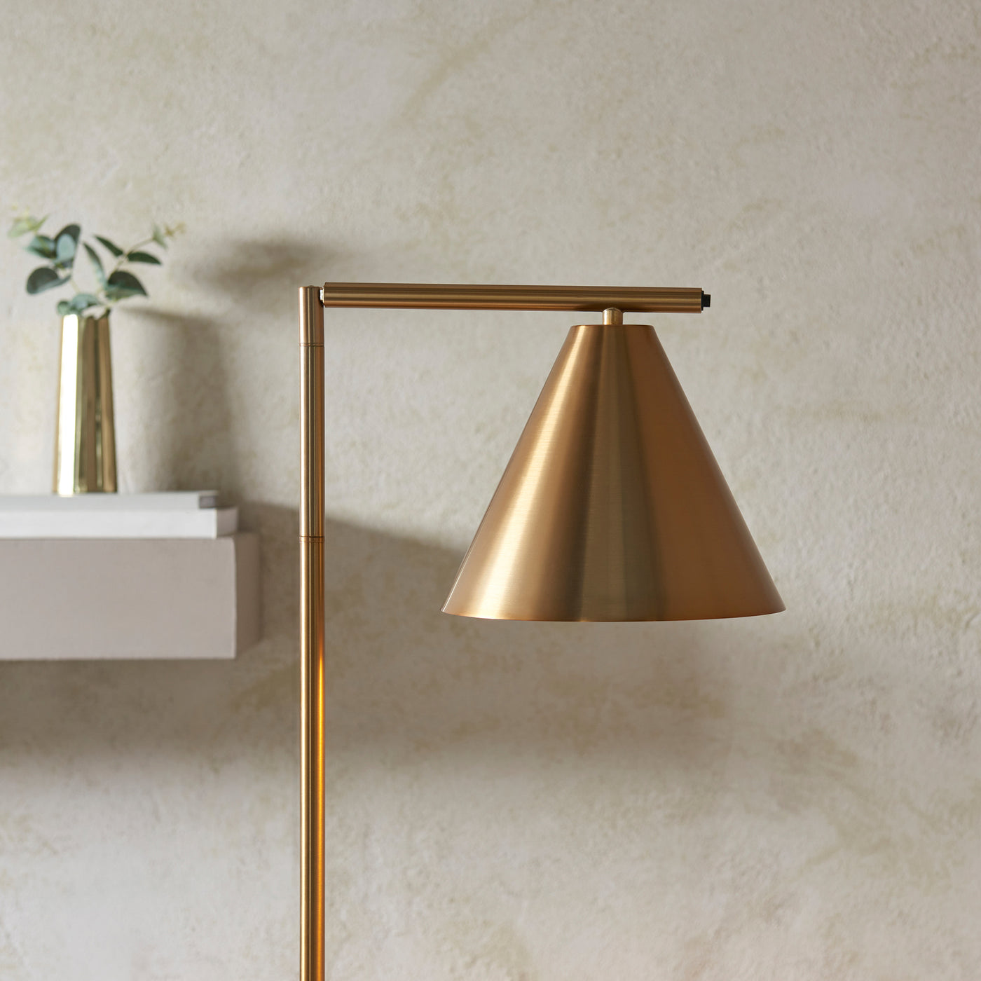 close up on top of tall slim lamp with conical head in antique brass colour