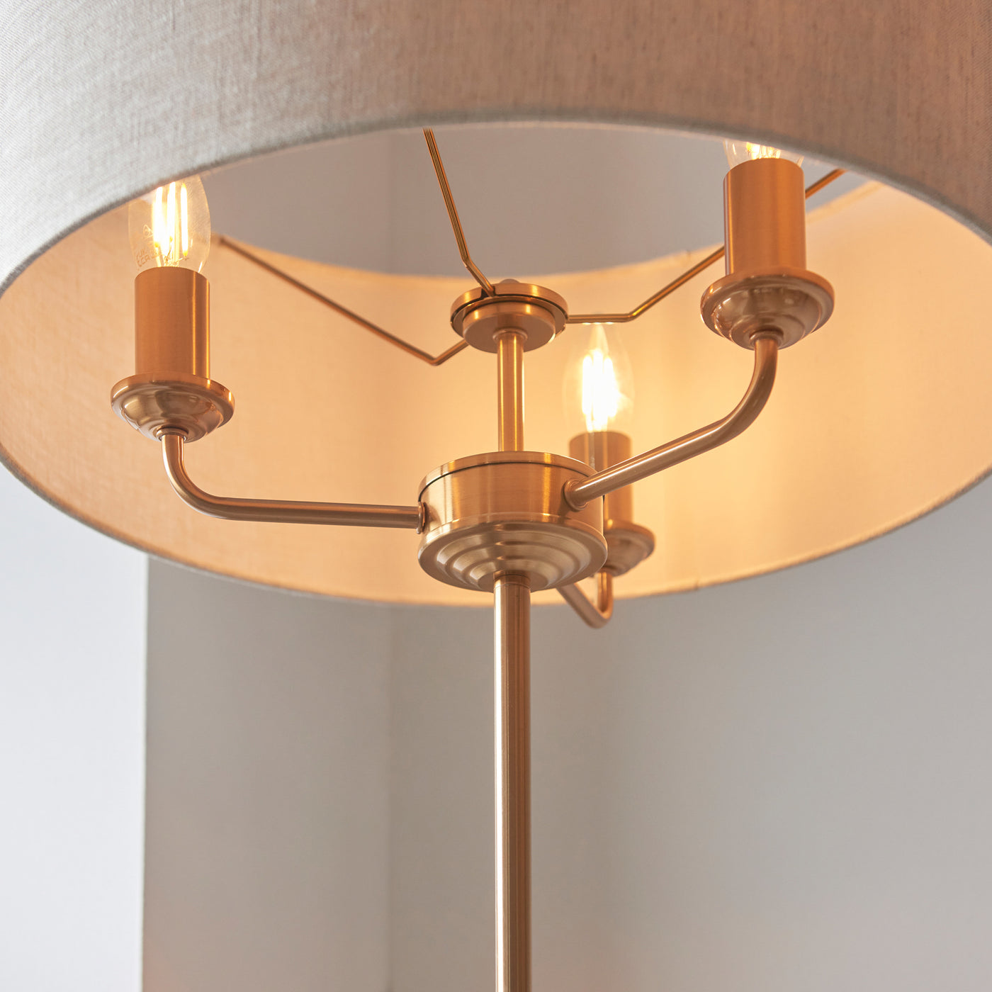 close up on underneath of lamp shade, showing three arms of lamp emitting warm glow from three bulbs