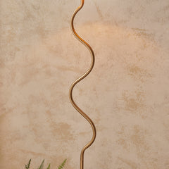 close up on wriggle-shaped body of brass floor lamp