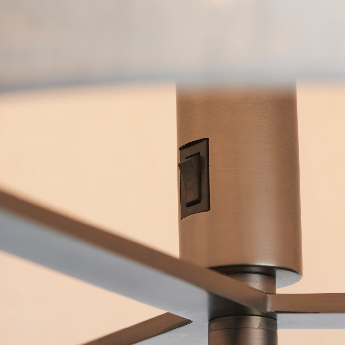 close up on subtle switch on part of bronze body floor lamp where the body goes up into the linen shade