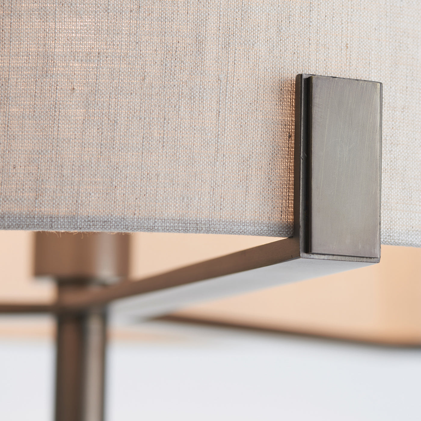 close up on bronze plated metalwork of floor lamp, where it directly supports the natural linen shade