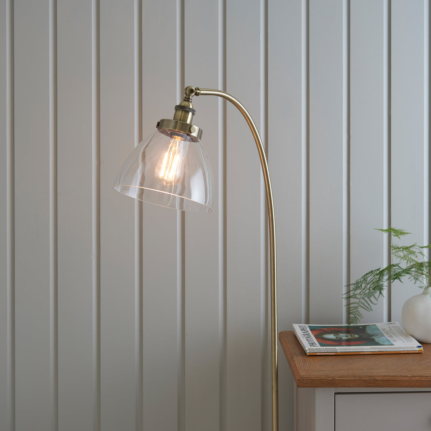 close up on top of gently arched antique brass floor lamp with clear shade