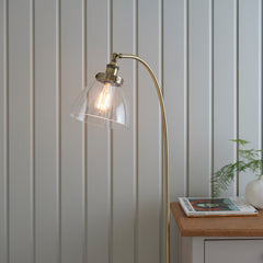 close up on top of gently arched antique brass floor lamp with clear shade