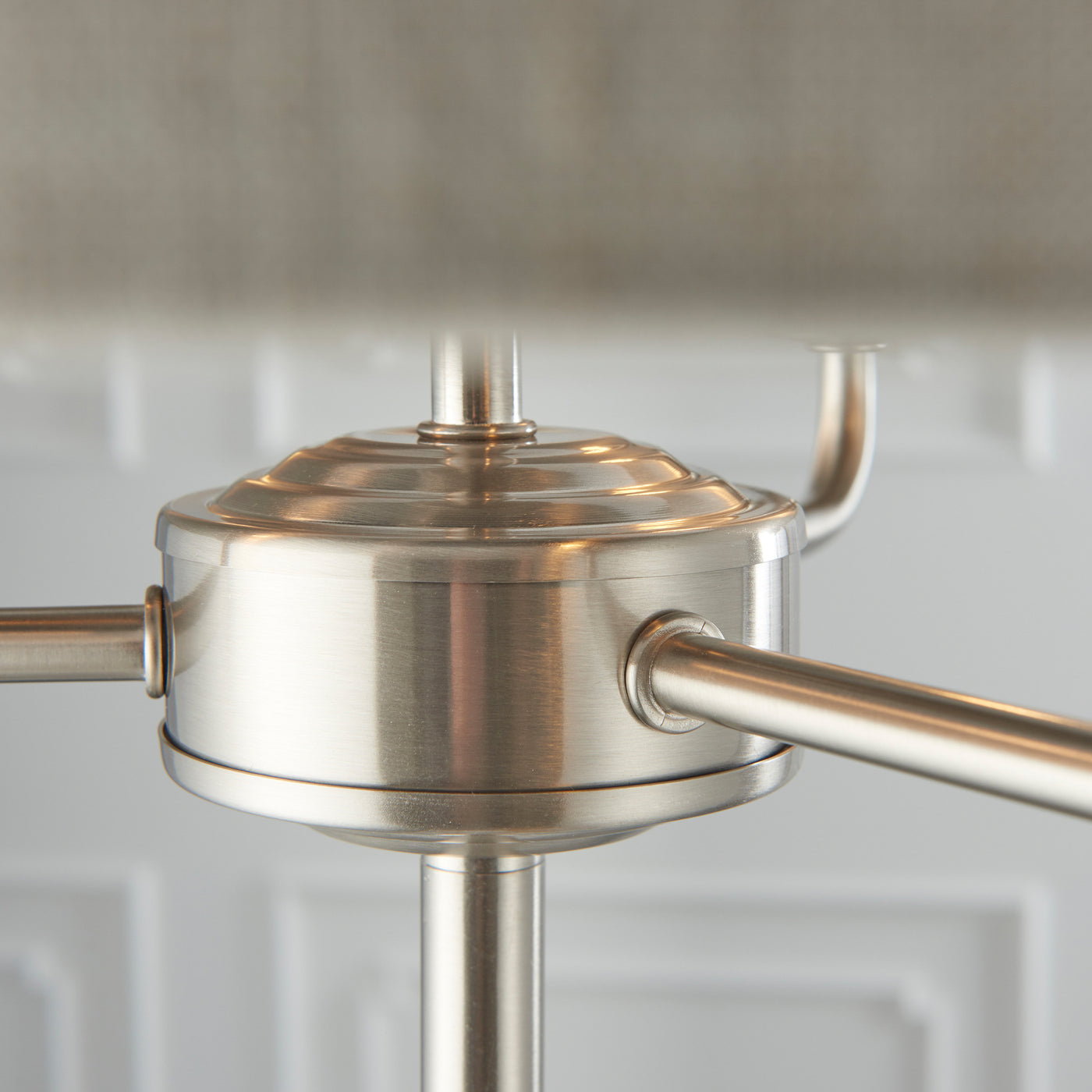 close up image of chrome-effect metalwork underneath shade of three armed lamp
