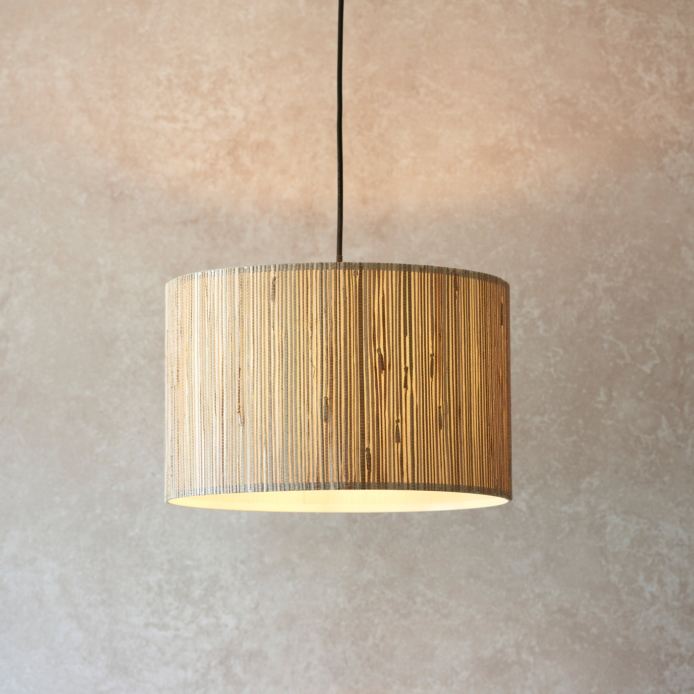 image of natural woven seagrass pendant light with black fixture hanging from a ceiling