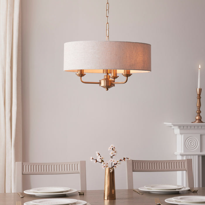 image of vintage brass three arm pendant light with natural shade over a dining room table