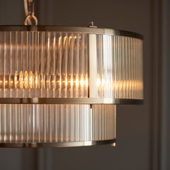 close up image of ribbed glass tiered pendant light, emitting warm glow from within