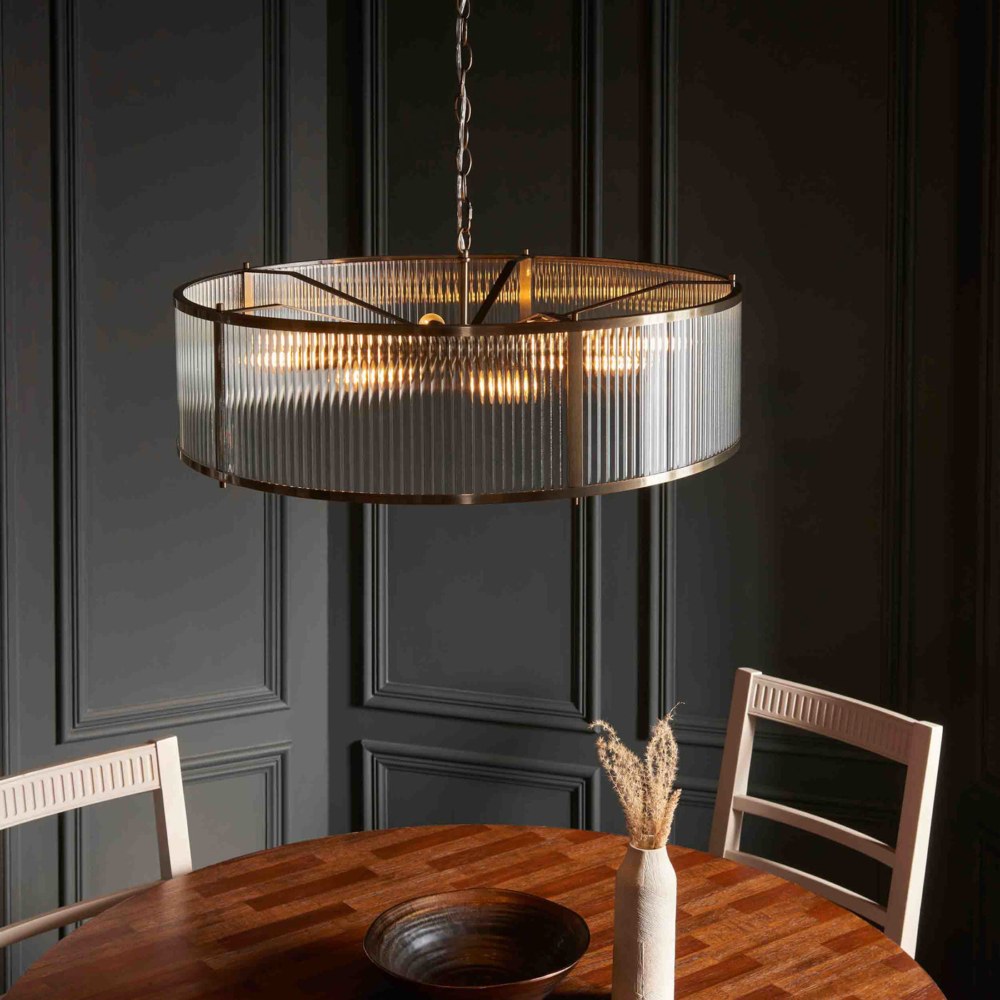 slightly angled image of ribbed glass pendant light emitting warm light from 8 bulbs within
