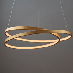 image of scribble-shape pendant light in gold, in front of dark grey wall