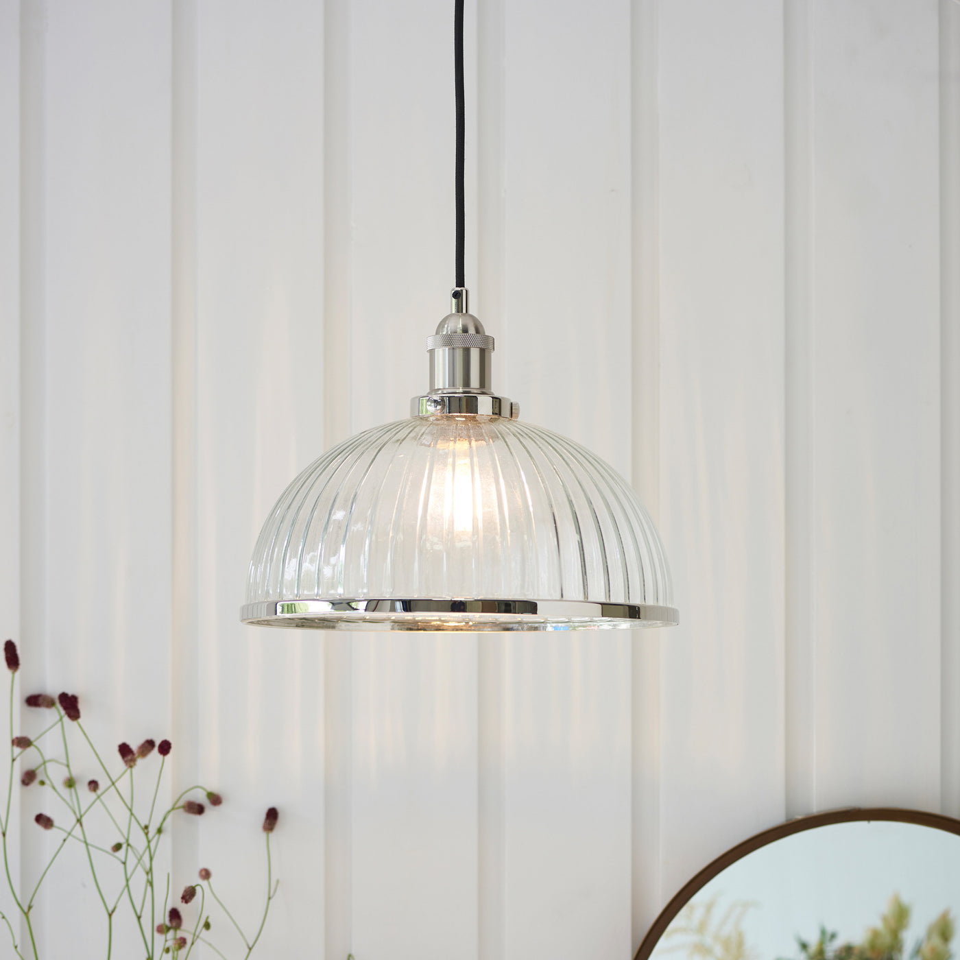 image of ribbed glass pendant light shade with nickel knurled detail, hanging in front of cream panelled wall