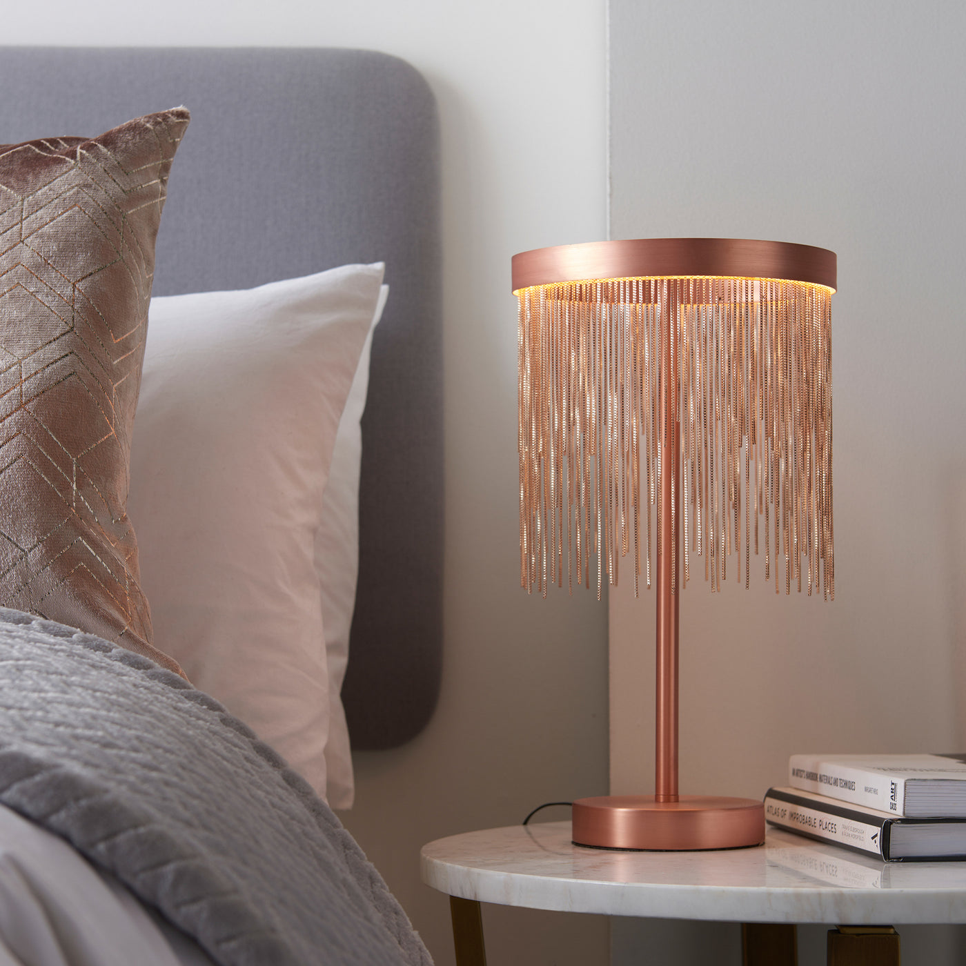 image of brushed copper fringe tasselled table lamp on a bedside table