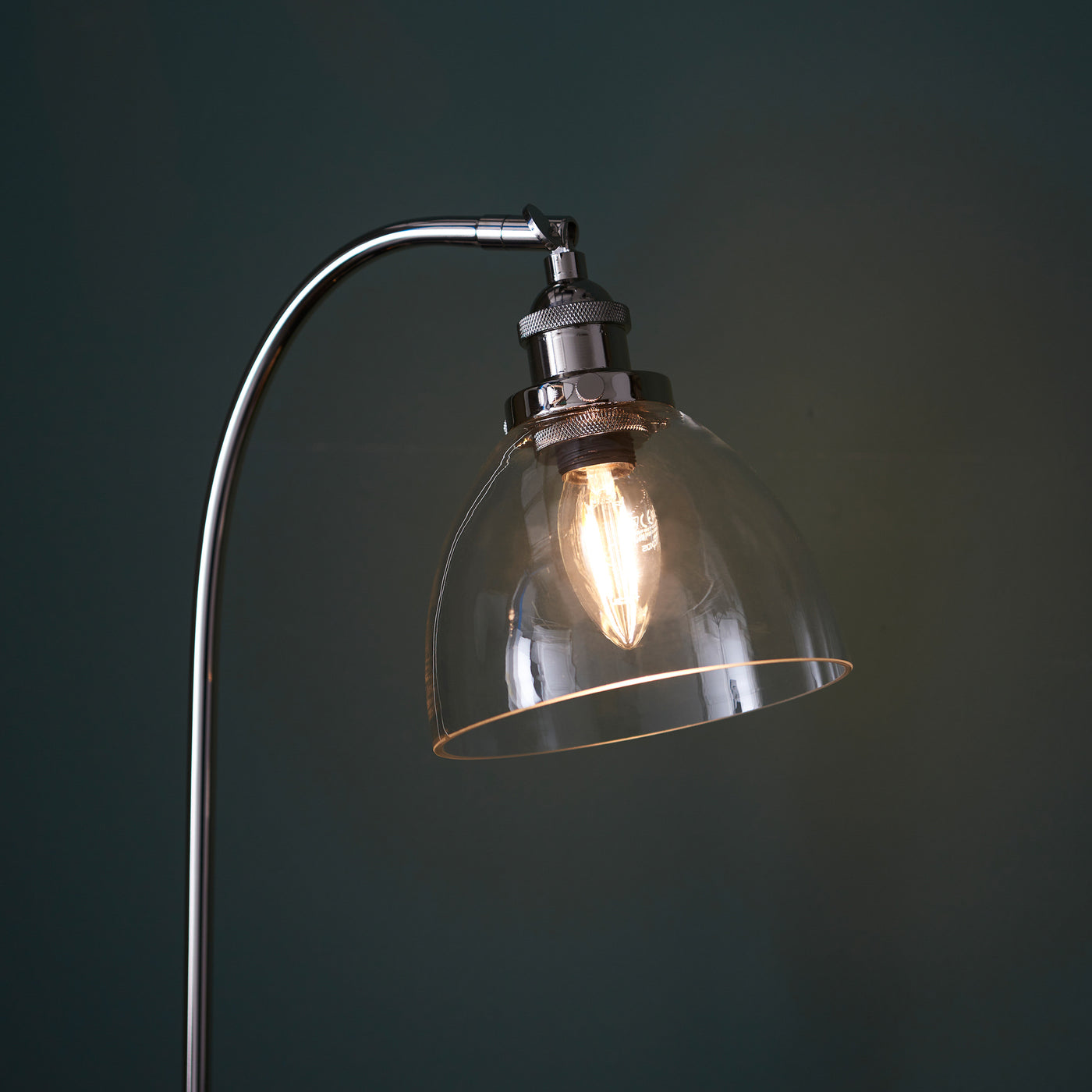 close up image of top of gently arched nickel table lamp with clear glass shade
