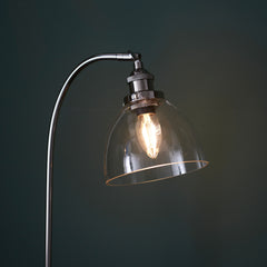 close up image of top of gently arched nickel table lamp with clear glass shade