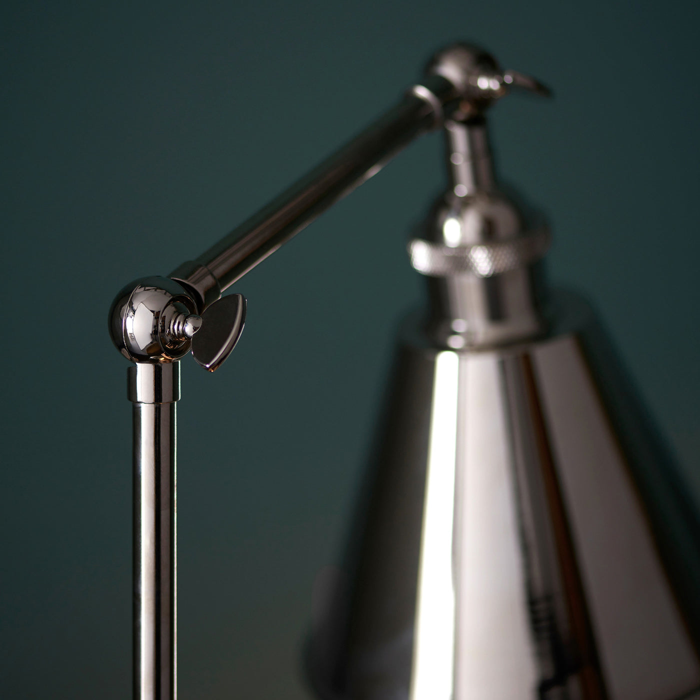 close up image of knuckle-contraption where slim body of table lamp meets the arm connecting it to the conical nickel shade