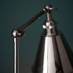 close up image of knuckle-contraption where slim body of table lamp meets the arm connecting it to the conical nickel shade