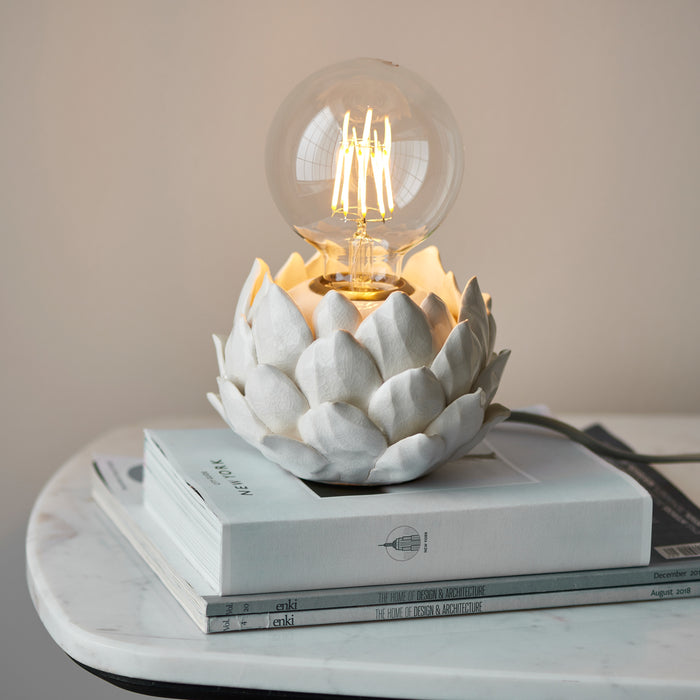 image of round lamp base with artichoke texture in oatmeal colour, on top of a pile of white books