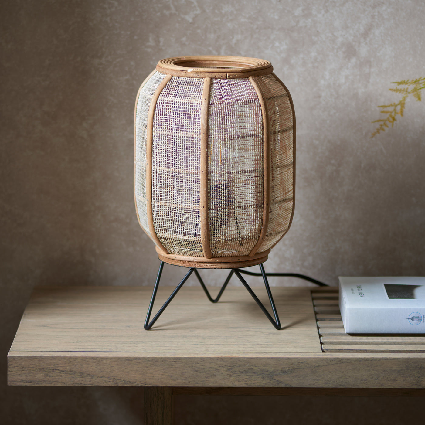 angled above image of table lamp with wooden and fabric shade, and black metal legs, on a wooden side table