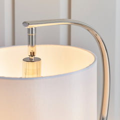 close up image of faux silk white table lamp surrounding nickel bulb fixture, focus on where nickel body curves into the shade