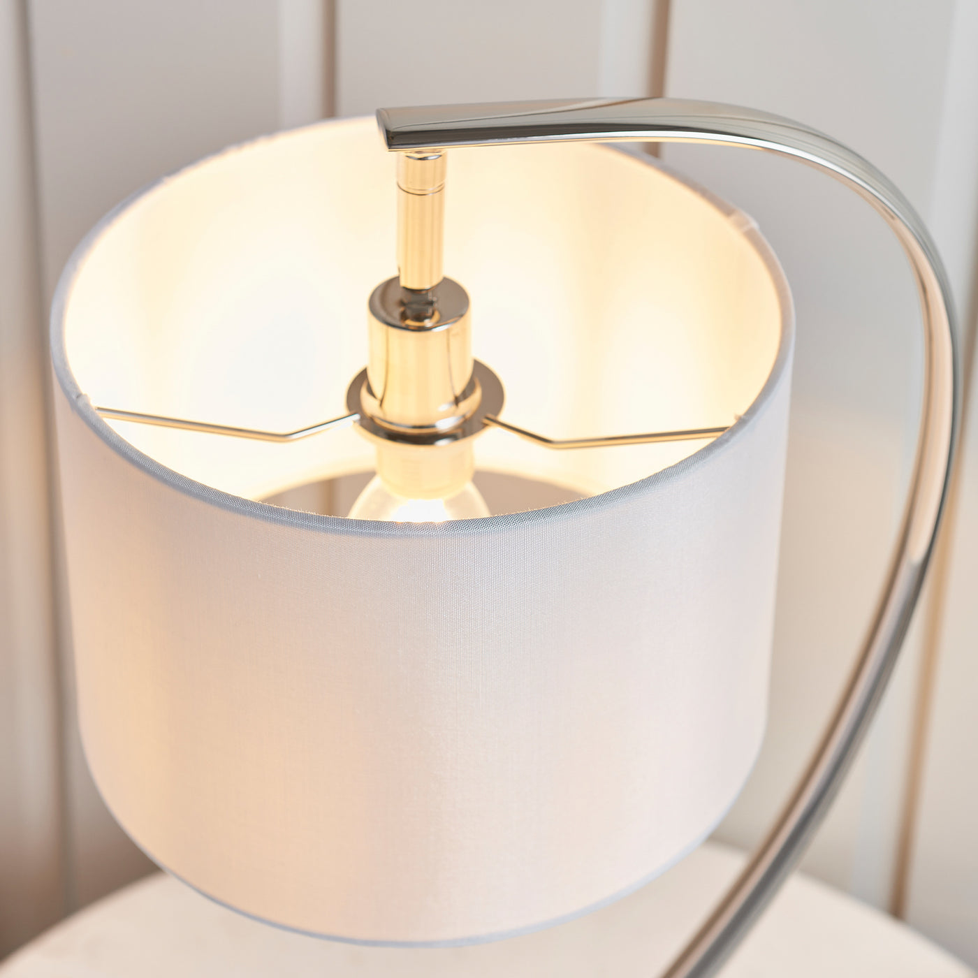 image taken slightly from above of nickel lamp body curving into faux silk lamp shade