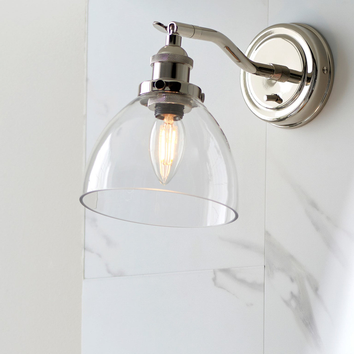 image of wall light with clear glass shade and nickel fixture on a marble-effect kitchen wall