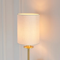 close up on cylindrical linen shade of satin brass wall light